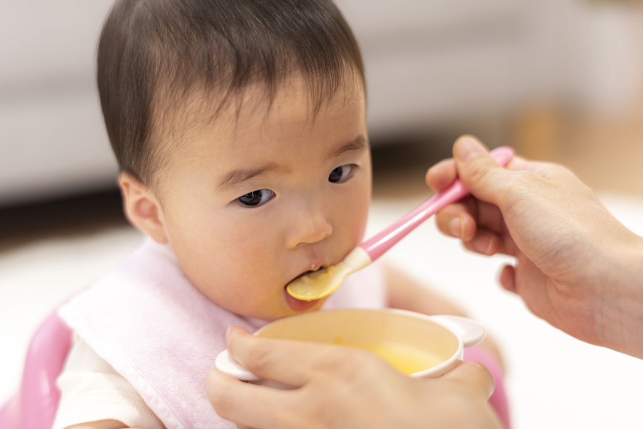 Mother feeds 0-year-old baby with baby food