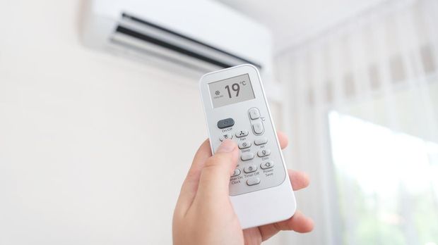 Hand with remote control directed on air conditioner. Home air conditioning concept