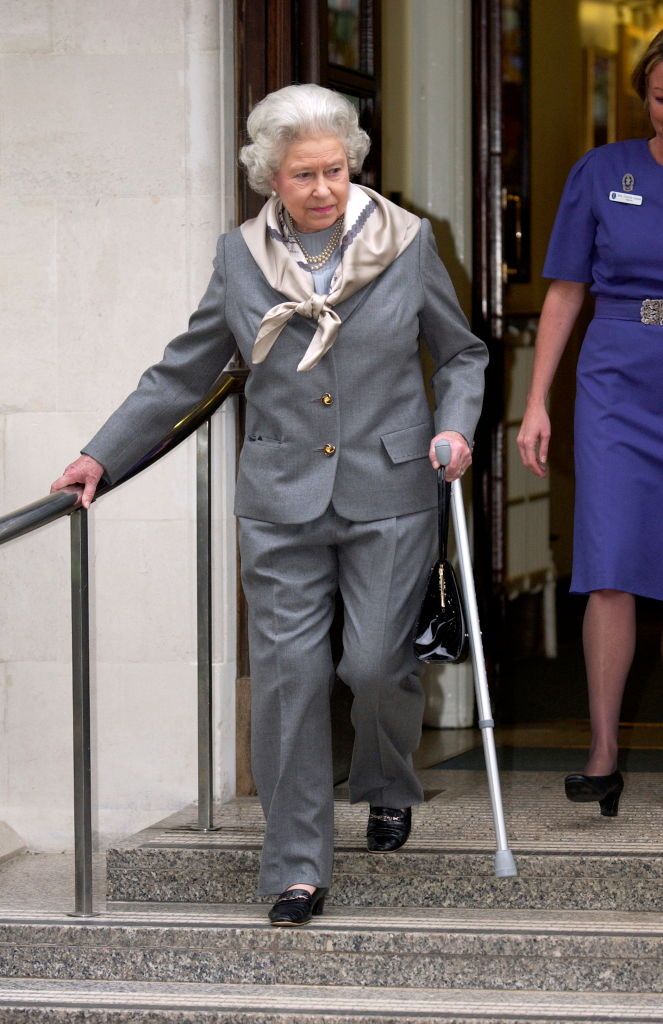 LONDON, UNITED KINGDOM - JANUARY 14:  Queen Elizabeth II  Carefully Stepping Out From The King Edward Vii Hospital  Holding A Walking Stick And Wearing A Trouser Suit To Cover Her Injured Knee.  (Photo by Tim Graham Photo Library via Getty Images)