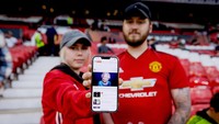 Dua fans Manchester United menunjukkan potongan berita wafatnya Ratu Elizabeth II. (Foto: Getty Images/Soccrates Images)