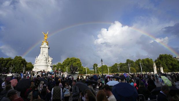 People gather outside Buckingham Palace in London as a double rainbow appears in the sky, Thursday, Sept. 8, 2022. Buckingham Palace says Queen Elizabeth II has been placed under medical supervision because doctors are 