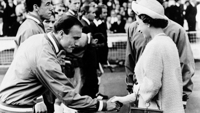 Piala Dunia 1966 English defender George Cohen, with teammate goalkeeper Gordon Banks standing next to him, bows his head as he shakes hand with Queen Elizabeth II of England 11 July 1966 at Wembley stadium in London before the start of the World Cup opening match between the host country and Uruguay. (Photo by STAFF / AFP) (Photo by STAFF/AFP via Getty Images)