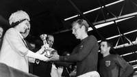 Ratu Elizabeth II dengan trofi Jules Rimet yang diterima kapten Inggris Bobby Moore. Foto: AFP via Getty Images/-