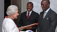 Dwight Yorke, legenda MU yang juga eks-pemain timnas Trinidad-Tobago, memberikan bola kepada Ratu Elizabeth. Momen itu terjadi ketika Ratu menyambangi Trinidad. Foto: PA Images via Getty Images/Chris Radburn - PA Images