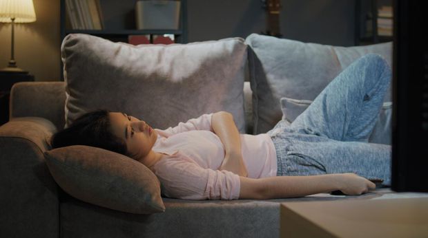 Asian Teenager Boring while watching tv at home in the nighttime.