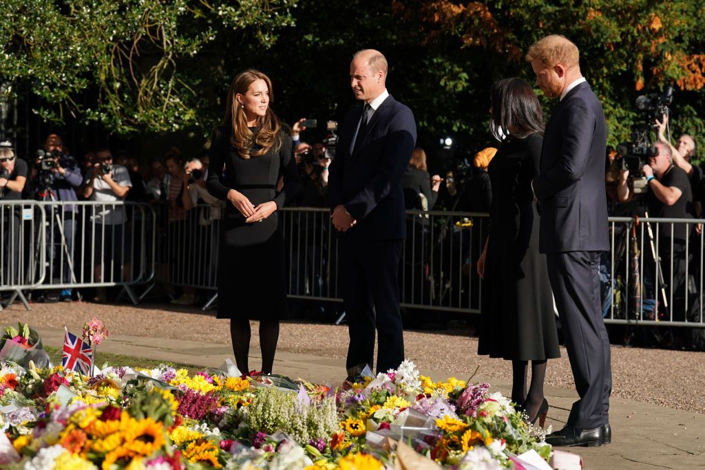 1422564352 WINDSOR, ENGLAND - SEPTEMBER 10: Prince Harry, Duke of Sussex, Meghan, Duchess of Sussex, Prince William, Prince of Wales and Catherine, Princess of Wales look at floral tributes laid by members of the public on the Long walk at Windsor Castle on September 10, 2022 in Windsor, England. Crowds have gathered and tributes left at the gates of Windsor Castle to Queen Elizabeth II, who died at Balmoral Castle on 8 September, 2022. (Photo by Chris Jackson - WPA Pool/Getty Images)