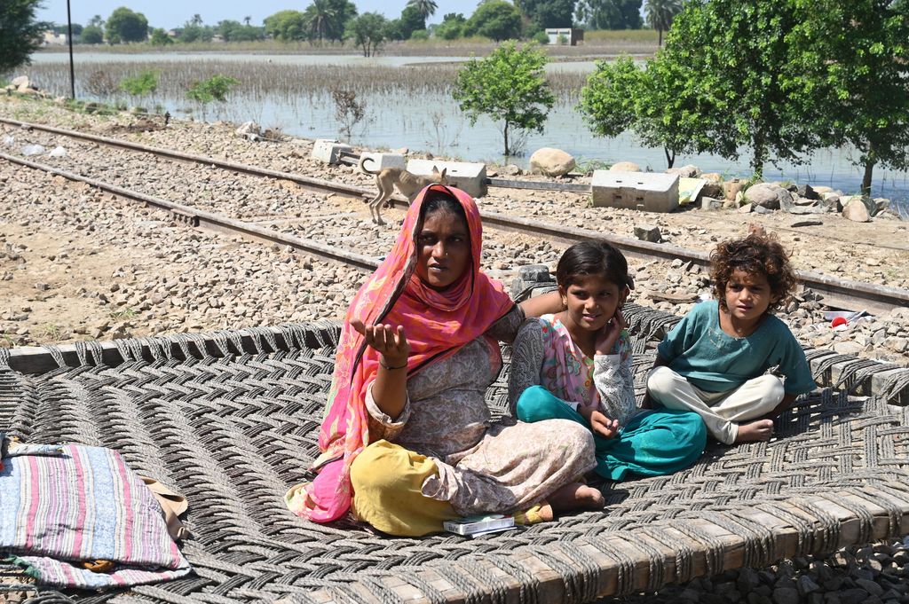 Fahmidah, a pregnant flood-affected woman sits with her children near her tent at a makeshift camp along a railway track in Fazilpur, Rajanpur district of Punjab province on September 3, 2022. - Monsoon rains have submerged a third of Pakistan, claiming at least 1,190 lives since June and unleashing powerful floods that have washed away swathes of vital crops and damaged or destroyed more than a million homes. (Photo by Arif ALI / AFP) (Photo by ARIF ALI/AFP via Getty Images)