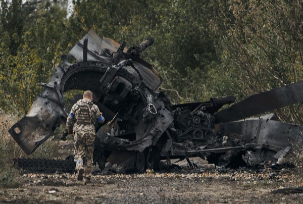 A Ukrainian soldier passes by a Russian tank damaged in a battle in a just freed territory on the road to Balakleya in the Kharkiv region, Ukraine, Sunday, Sept. 11, 2022. (AP Photo)