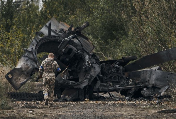 Tentara Ukraina memeriksa tank militer Rusia yang rusak dalam pertempuran di Balakleya, yang baru dibebaskan dari pasukan Moskow A Ukrainian soldier passes by a Russian tank damaged in a battle in a just freed territory on the road to Balakleya in the Kharkiv region, Ukraine, Sunday, Sept. 11, 2022. (AP Photo)