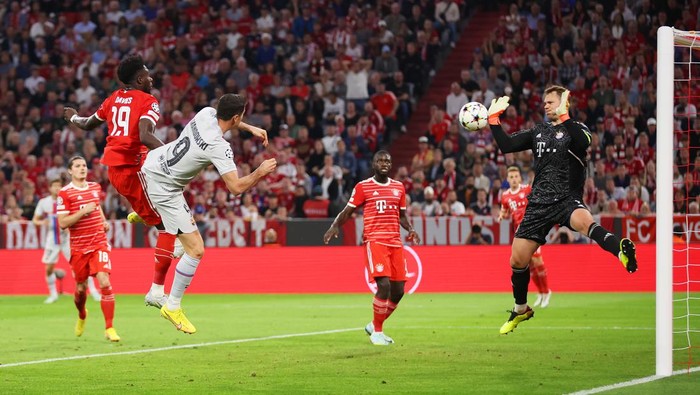 MUNICH, GERMANY - SEPTEMBER 13: Alphonso Davies of Bayern Munich contends for the aerial ball with Robert Lewandowski of FC Barcelona as their header is saved by Manuel Neuer during the UEFA Champions League group C match between FC Bayern München and FC Barcelona at Allianz Arena on September 13, 2022 in Munich, Germany. (Photo by Alex Grimm/Getty Images)