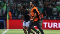 Petugas keamanan membawa seorang fan keluar lapangan pertandingan usai menerobos masuk untuk memeluk Messi.