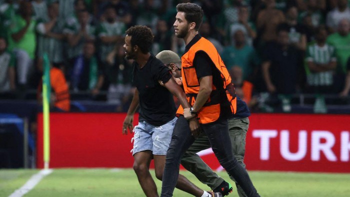 Detik-detik Fan Terobos Lapangan Demi Peluk Messi A steward interferes as a pitch invader hugs Paris Saint-Germain's Argentine forward Lionel Messi during the UEFA Champions League group H football match between Israel's Maccabi Haifa and France's Paris Saint-Germain (PSG) at the Sammy Ofer stadium in the city of Haifa on September 14, 2022. (Photo by RONALDO SCHEMIDT / AFP) (Photo by RONALDO SCHEMIDT/AFP via Getty Images)
