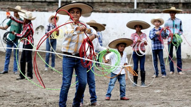 Students practice with a rein at the municipal Charreria school in Tlajomulco de Zuiga, state of Jalisco, Mexico, on August 31, 2022. - A charro is a Mexican horseman or cowboy, typically one wearing an elaborate outfit, often with silver decorations, of tight trousers, ruffled shirt, short jacket, and sombrero. The traditional charro competition charreada or charreria (similar to a rodeo) has become the official sport of Mexico and maintains traditional rules and regulations in effect from colonial times up to the Mexican Revolution. In 2016 it was declared Intangible Cultural Heritage of Humanity by UNESCO. (Photo by ULISES RUIZ / AFP)