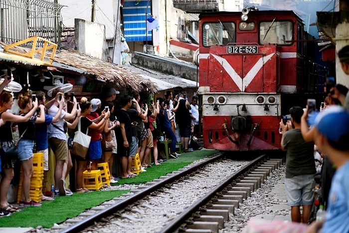 Sedih, Wisata Rel Kereta di Gang Sempit Vietnam Kini Ditutup This photograph taken on June 9, 2019 shows a family posing for a selfie on the railway track in Hanois popular train street. (Photo by Manan VATSYAYANA / AFP)(Photo credit should read MANAN VATSYAYANA/AFP via Getty Images)
