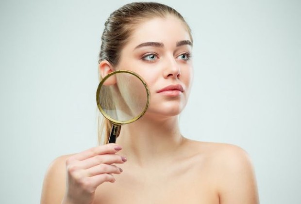 Perempuan sedang memegang kaca pembesar