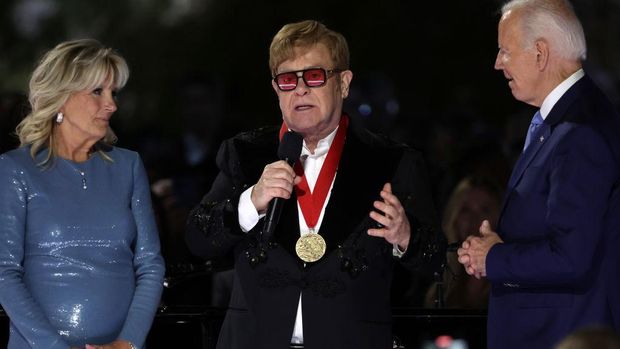 WASHINGTON, DC - SEPTEMBER 23: British singer-songwriter Sir Elton John (2nd L) speaks after he was presented with the National Humanities Medal by U.S. President Joe Biden (R) as first lady Jill Biden (L) looks on during an event at the South Lawn of the White House on September 23, 2022 in Washington, DC. President Joe Biden and first lady Jill Biden hosted the event titled “A Night When Hope and History Rhyme,” to “celebrate the unifying and healing power of music, commend the life and work of Sir Elton John, and honor the everyday history-makers in the audience, including teachers, nurses, frontline workers, mental health advocates, students, LGBTQ+ advocates and more.” (Photo by Alex Wong/Getty Images)