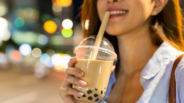 asian woman is holding bubble pearl milk tea outdoor in the evening