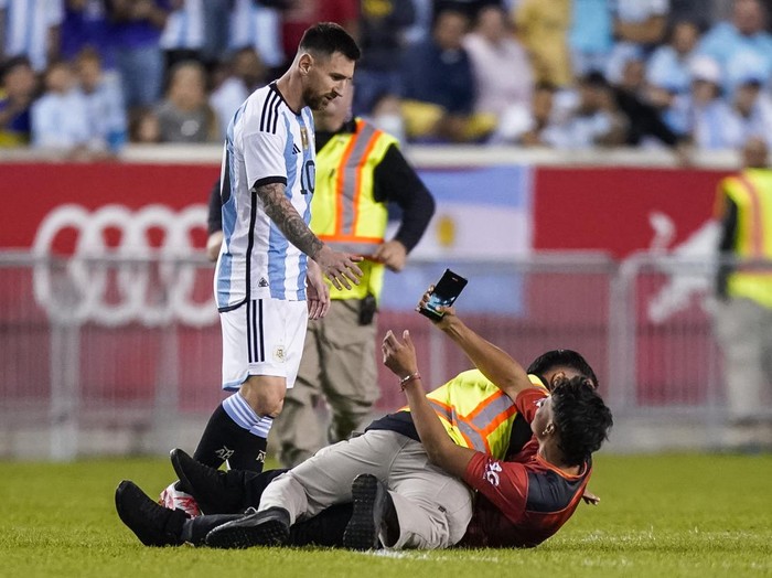 A fan is tackled as he tries to take a picture of Argentina's player Lionel Messi during the second half of an international friendly soccer match against Jamaica on Tuesday, Sept. 27, 2022, in Harrison, N.J. (AP Photo/Eduardo Munoz Alvarez)