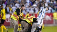 Tapi baru saja Messi menggores spidol ke punggung si suporter, petugas keburu menabraknya. Messi juga ikut tertabrak petugas, lihat tuh sampai tubuhnya agak limbung. Jelang laga berakhir, sempat ada suporter lain lagi yang masuk ke lapangan tapi juga berhasil diamankan oleh petugas. (Foto: AP/Eduardo Munoz Alvarez)