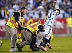 Tapi baru saja Messi menggores spidol ke punggung si suporter, petugas keburu menabraknya. Messi juga ikut tertabrak petugas, lihat tuh sampai tubuhnya agak limbung. Jelang laga berakhir, sempat ada suporter lain lagi yang masuk ke lapangan tapi juga berhasil diamankan oleh petugas. (Foto: AP/Eduardo Munoz Alvarez)