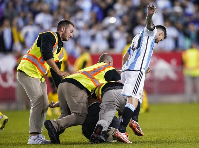A fan is tackled as he tries to take a selfie with Argentina's player Lionel Messi as he celebrates his goal during the second half of an international friendly soccer match against Jamaica on Tuesday, Sept. 27, 2022, in Harrison, N.J. (AP Photo/Eduardo Munoz Alvarez)