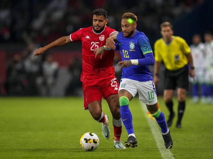 Brazil's Neymar has a laser light on his face as he duels for the ball with Tunisia's Anis Ben Slimane during the international friendly soccer match between Brazil and Tunisia at the Parc des Princes stadium in Paris, France, Tuesday, Sept. 27, 2022. (AP Photo/Christophe Ena)