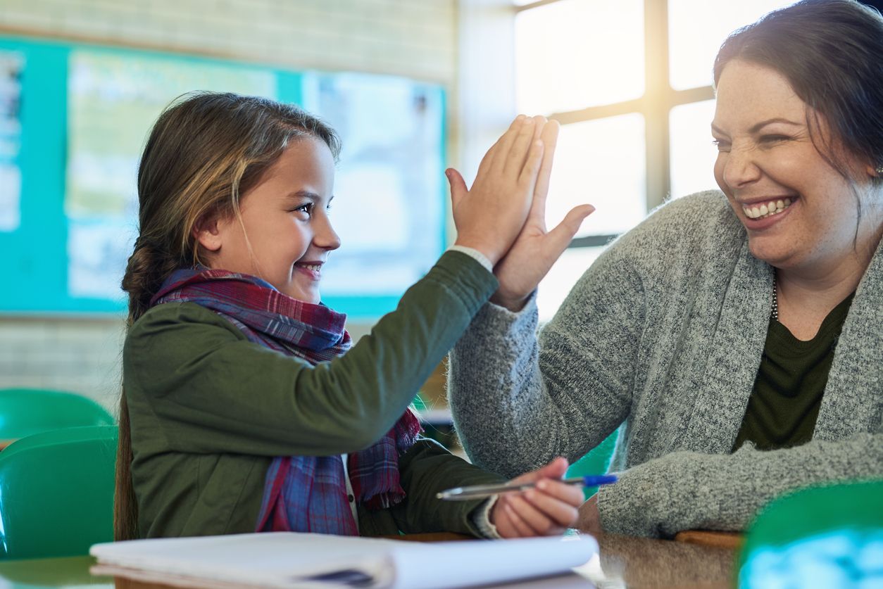 Shot of an elementary school girl high fiving her teacher in class