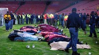 Sejumlah mayat dikumpulkan di lapangan saat tragedi ketusuhan di laga Chiefs vs Orlando Pirates berlangsung di Stadion Ellis Park, Johannesburg, Afrika Selatan, 11 April 2001. Tragedi ini mengakibatkan 42 suporter meninggal akibat kerusuhan. Tindakan petugas keamanan yang berusaha membubarkan justru berujung kerusuhan yang lebih besar sehingga korban jiwa berjatuhan. (Dok. panditfootball.com)