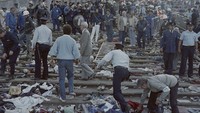 Tim penyelamat dan polisi mencari korban pada 29 Mei 1985 di lokasi kerusuhan di stadion sepak bola Heysel di Brussel, Belgia. Dalam kerusuhan tersebut mengakibatkan 39 orang tewas, satu jam sebelum Final Piala Eropa antara Liverpool dari Inggris dan Juventus dari Turin, Italia. Tragedi itu terjadi ketika dinding stadion runtuh di bawah tekanan orang-orang dan menghancurkan penggemar Juventus ketika mereka mencoba melarikan diri dari pendukung Liverpool. (Dominique Faget/Getty Images)