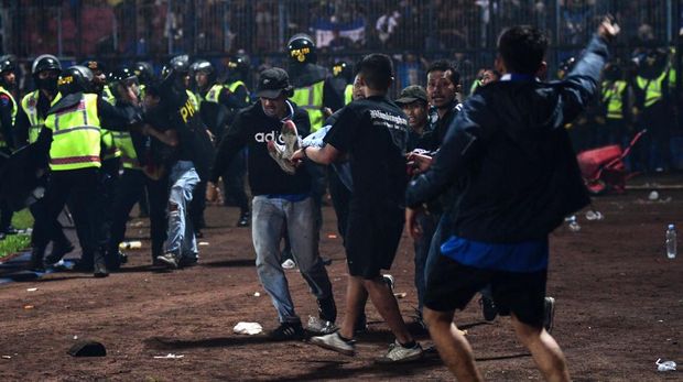 In this picture taken on October 1, 2022, a group of people carry a man after a football match between Arema FC and Persebaya Surabaya at Kanjuruhan stadium in Malang, East Java. - At least 127 people died at a football stadium in Indonesia late on October 1 when fans invaded the pitch and police responded with tear gas, triggering a stampede, officials said. (Photo by AFP) (Photo by STR/AFP via Getty Images)