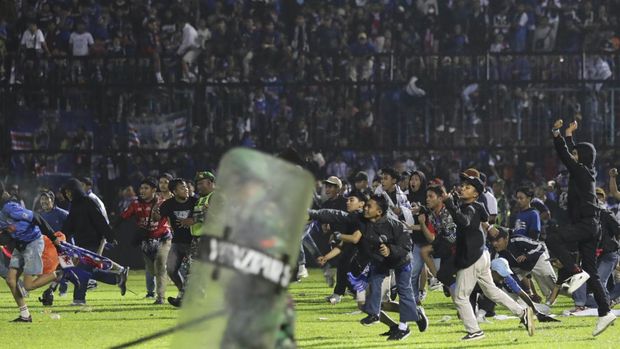 Soccer fans enter the pitch during a clash between supporters at Kanjuruhan Stadium in Malang, East Java, Indonesia, Saturday, Oct. 1, 2022. Panic following police actions left over 100 dead, mostly trampled to death, police said Sunday. (AP Photo/Yudha Prabowo)