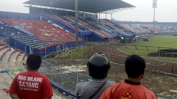 People examine the damage following a soccer match stampede at the Kanjuruhan Stadium in Malang, East Java, Indonesia, Sunday, Oct. 2, 2022. Panic at an Indonesian soccer match after police fired tear gas to to disperse supporters invading the pitch left over 100 people dead, mostly trampled to death, police said Sunday. (AP Photo/Hendra Permana)