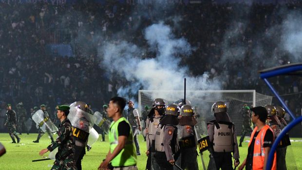 This picture taken on October 1, 2022 shows tear gas let off by police amongst people crowded in the stands after a football match between Arema FC and Persebaya at the Kanjuruhan stadium in Malang, East Java. - Anger against police mounted in Indonesia on October 3 after at least 125 people were killed in one of the deadliest disasters in the history of football, when officers fired tear gas in a packed stadium, triggering a stampede. (Photo by AFP)