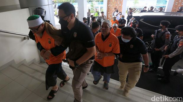 Sepuluh orang tersangka kasus Khilafatul Muslimin diserahkan ke Kejari Bekasi. Polisi bersenjata laras panjang mengawal proses penyerahan para tersangka.