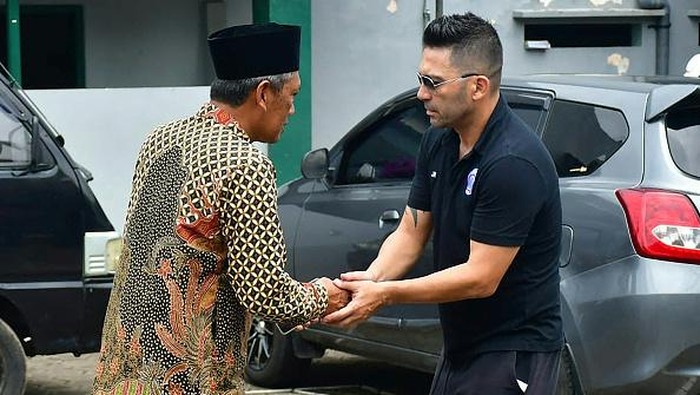Momen Pemain Arema Ziarah ke Makam Korban Kanjuruhan Pelatih Arema FC Javier Roca (kanan) berjabat tangan dengan kerabat korban tragedi Kanjuruhan di Gondanglegi, Kabupaten Malang, Jawa Timur, Senin (3/10/2022). Setelah melakukan tabur bunga di Stadion Kanjuruhan, rombongan yang terdiri dari pelatih, pemain, dan ofisial Arema FC bergerak ke Pondok Pesantren Miftahul Ulum Atthohirin, Gondanglegi. (Putri/AFP/Getty Images)