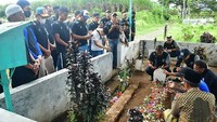 Para pemain Arema FC berdoa di makam korban tragedi Kanjuruhan di Gondanglegi, Kabupaten Malang, Jawa Timur, Senin (3/10/2022). Salah seoran perwakilan keluarga almarhum, Abdus Syukur, mengaku senang dengan perhatian yang diberikan skuad Arema FC ini. Menurut sepupu korban tersebut, kehadiran Javier Roca dan tim mampu memberi sedikit kebahagiaan di tengah duka yang dirasakan keluarga. (Putri/AFP/Getty Images)  