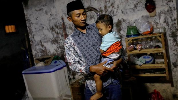 Andi Hariyanto, 36, a husband who lost his wife and two adopted children in a recent riot and stampede following a soccer match between Arema FC and Persebaya Surabaya at Kanjuruhan stadium, carries his 2-year-old son Gean Putra Hariyanto, at his house in Malang, East Java province, Indonesia, October 4, 2022. REUTERS/Willy Kurniawan REFILE - CORRECTING RELATIONSHIP AND AGE