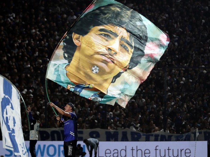 gimnasia la plata vs boca juniors,gas air mata,polisi,suporter Gimnasia y Esgrima's fans wave flags with the image of former Argentinian soccer star Diego Maradona before the Argentine Professional Football League Tournament 2022 match at Juan Carmelo Zerillo stadium in La Plata city, Buenos Aires, on October 6, 2022. - A supporter of the Gimnasia soccer club died during serious incidents that broke out during an Argentine league match between his team and Boca Juniors on Thursday in Buenos Aires, according to local authorities.