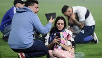Ibu dan anak terlihat lemas dan duduk di lapangan akibat gas air mata. (Foto: ALEJANDRO PAGNI/AFP via Getty Images)