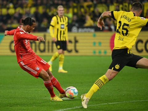 Bayern Munich's German midfielder Leroy Sane (L) shoots to score the 0-2 pas Dortmund's German defender Niklas Suele the German first division Bundesliga football match between BVB Borussia Dortmund and FC Bayern Munich in Dortmund, western Germany, on October 8, 2022. - DFL REGULATIONS PROHIBIT ANY USE OF PHOTOGRAPHS AS IMAGE SEQUENCES AND/OR QUASI-VIDEO (Photo by INA FASSBENDER / AFP) / DFL REGULATIONS PROHIBIT ANY USE OF PHOTOGRAPHS AS IMAGE SEQUENCES AND/OR QUASI-VIDEO (Photo by INA FASSBENDER/AFP via Getty Images)