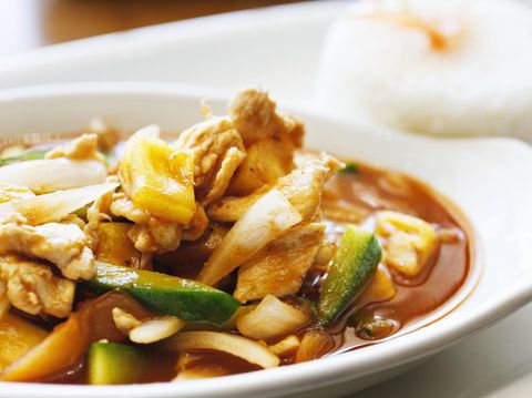 The Thai version of sweet and sour chicken with chilli, pineapple, cucumber and onions. A mound of rice sits in the background.