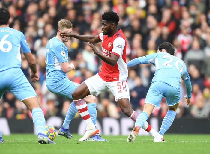 LONDON, ENGLAND - JANUARY 01: Thomas Partey of Arsenal takes on (L) Kevin De Bruyne and (R) Bernardo Silva of Man CIty during the Premier League match between Arsenal  and  Manchester City at Emirates Stadium on January 01, 2022 in London, England. (Photo by Stuart MacFarlane/Arsenal FC via Getty Images)