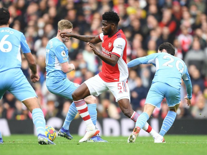 LONDON, ENGLAND - JANUARY 01: Thomas Partey of Arsenal takes on (L) Kevin De Bruyne and (R) Bernardo Silva of Man CIty during the Premier League match between Arsenal  and  Manchester City at Emirates Stadium on January 01, 2022 in London, England. (Photo by Stuart MacFarlane/Arsenal FC via Getty Images)