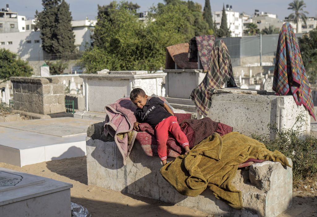 GAZA, PALESTINE - 2022/10/19: A Palestinian child plays in front of his house in Sheikh Shaban cemetery in Gaza City. There is a battle for space between the living and the dead as the homeless settle in cemeteries. Camelia Kahil, a resident, said that if the dead could speak, they would tell them to get out of there. Due to poverty, they don't have a choice but to live in the cemetery and endure the pungent smell, which they call 