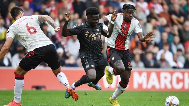 SOUTHAMPTON, ENGLAND - OCTOBER 23: Bukayo Saka of Arsenal challenged by Southampton defenders (L) Duje Caleta-Car and (R) Mohammed Salisu during the Premier League match between Southampton FC and Arsenal FC at Friends Provident St. Mary's Stadium on October 23, 2022 in Southampton, England. (Photo by Stuart MacFarlane/Arsenal FC via Getty Images)