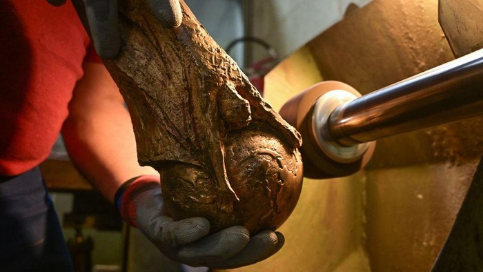 A worker applies manual chiselling and hammering to refine intricate details on a raw brass trophy, replica of the FIFA football World Cup Trophy, at the Italian trophy and medal manufacturer GDE Bertoni on October 12, 2022 in Paderno Dugnano, north of Milan. - While the original 18 carat gold trophy made by Italian artist Silvio Gazzaniga belongs to FIFA and is rarely exhibited, the GDE Bertoni factory is still tasked with producing brass gold-plated replicas of the trophy every four years for the winning team. (Photo by MIGUEL MEDINA / AFP) (Photo by MIGUEL MEDINA/AFP via Getty Images)