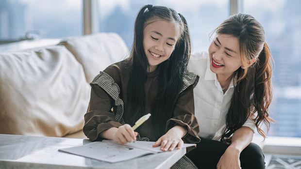 asian chinese young family mother daughter enjoying bonding time doing homework  at home during weekend in living room apartment