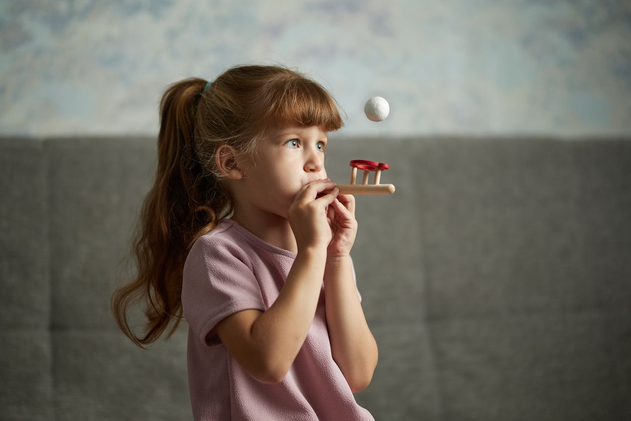 Little girl in class with a speech therapist . The use of special tools for speech correction.