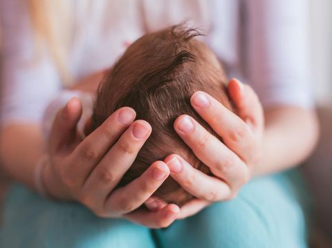 Mother holding newborn baby boy on her knees, closeup