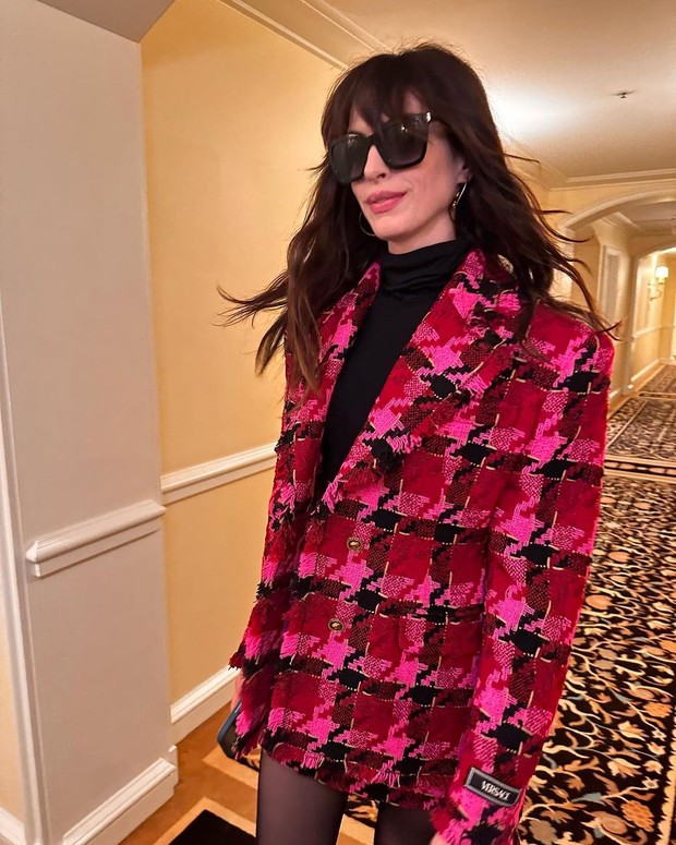 Anne Hathaway memakai blazer tweed berwarna pink fuschia dari Versace Anne Hathaway